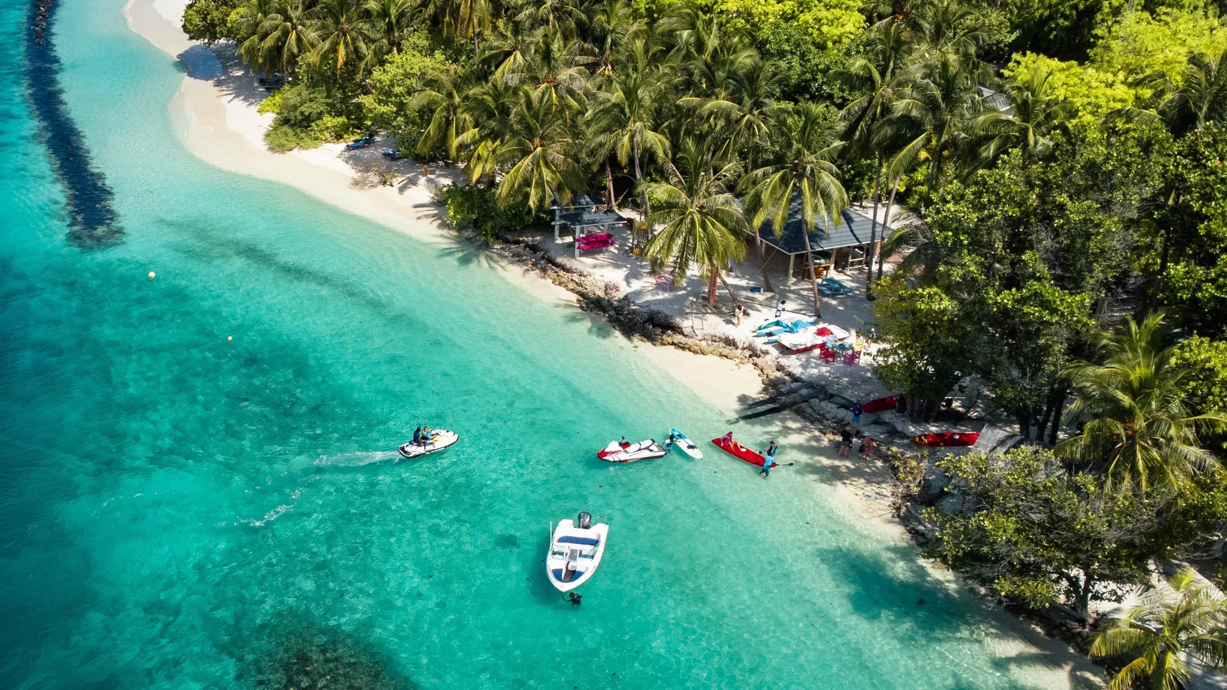 Boote vor einem palmengesäumten Strand auf den Malediven