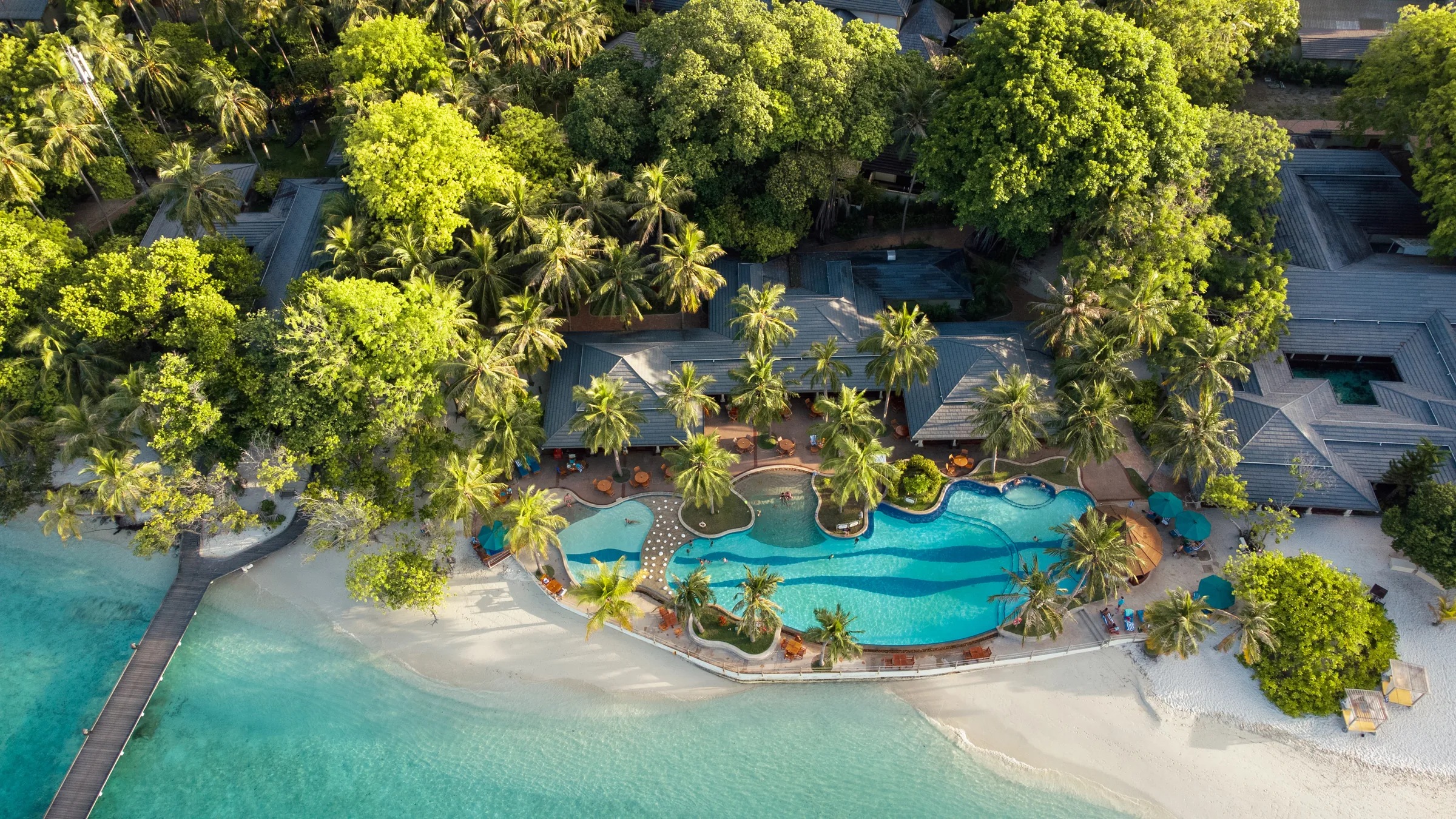 Poolanlage zwischen Palmen und Strand auf den Malediven